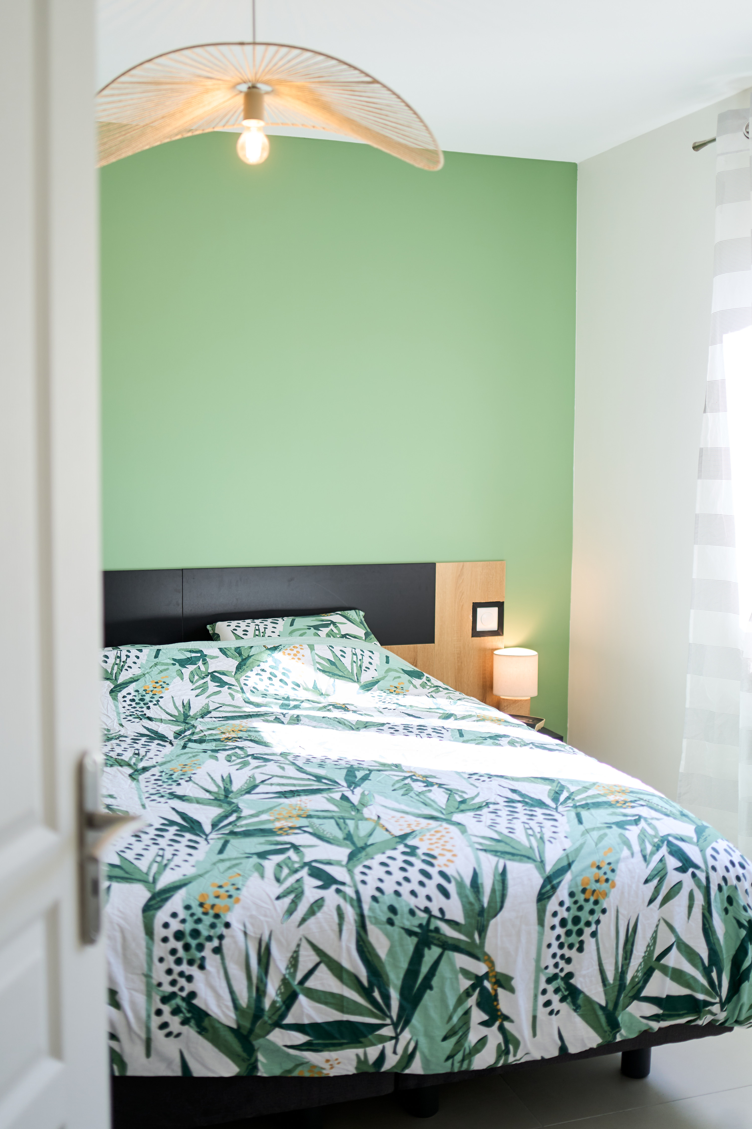 Chambre avec suspension ajourée, lampe de chevet et mur vert