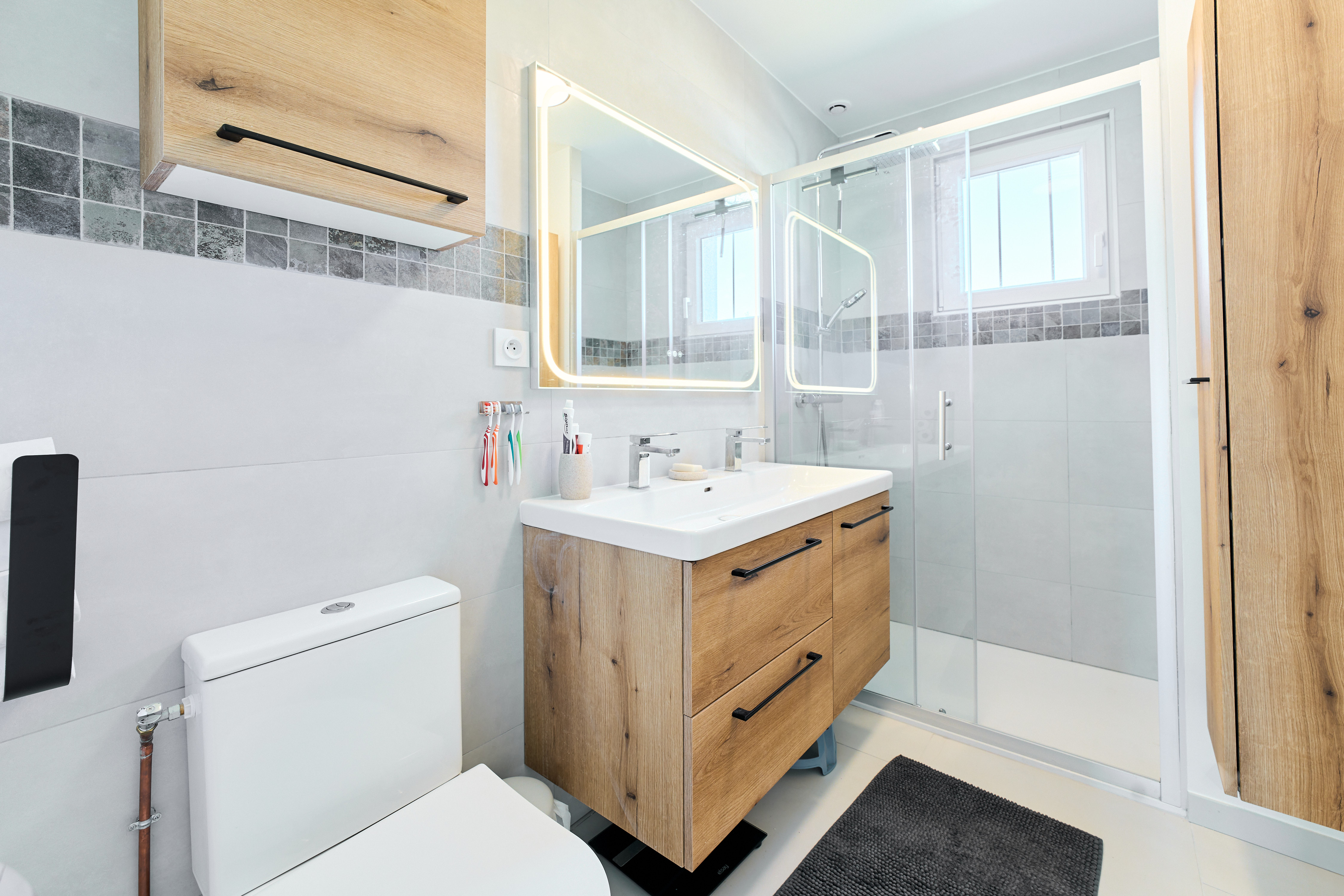Salle de bain avec miroir rétroéclairé et vasque double, éclairage type loges d'artistes