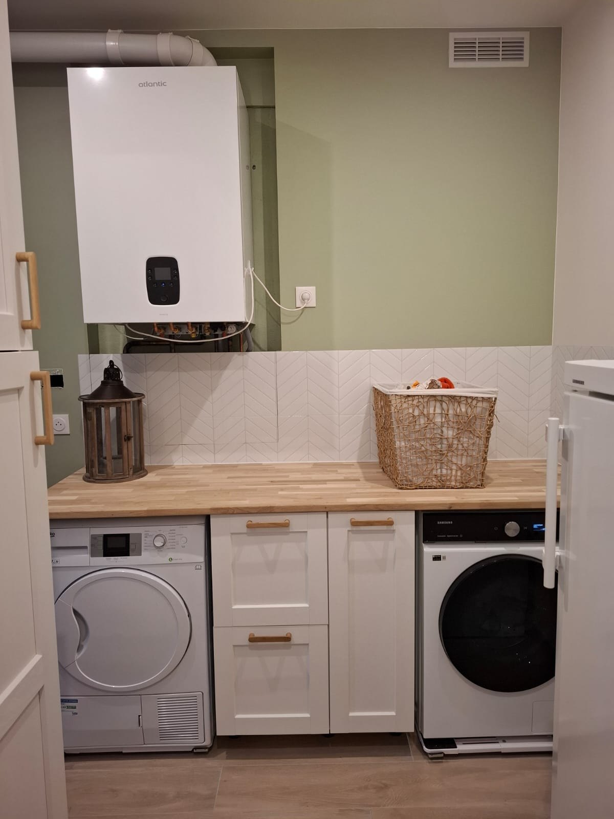 Buanderie fonctionnelle avec lave-linge et sèche-linge sous un plan de travail en bois à Yerres