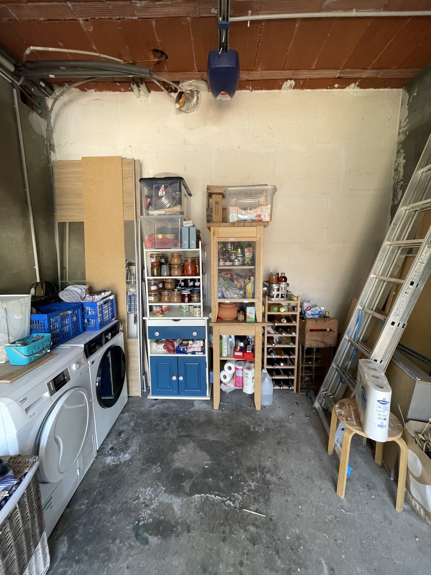Garage avant transformation avec lave-linge, sèche-linge et étagères de rangement à Yerres