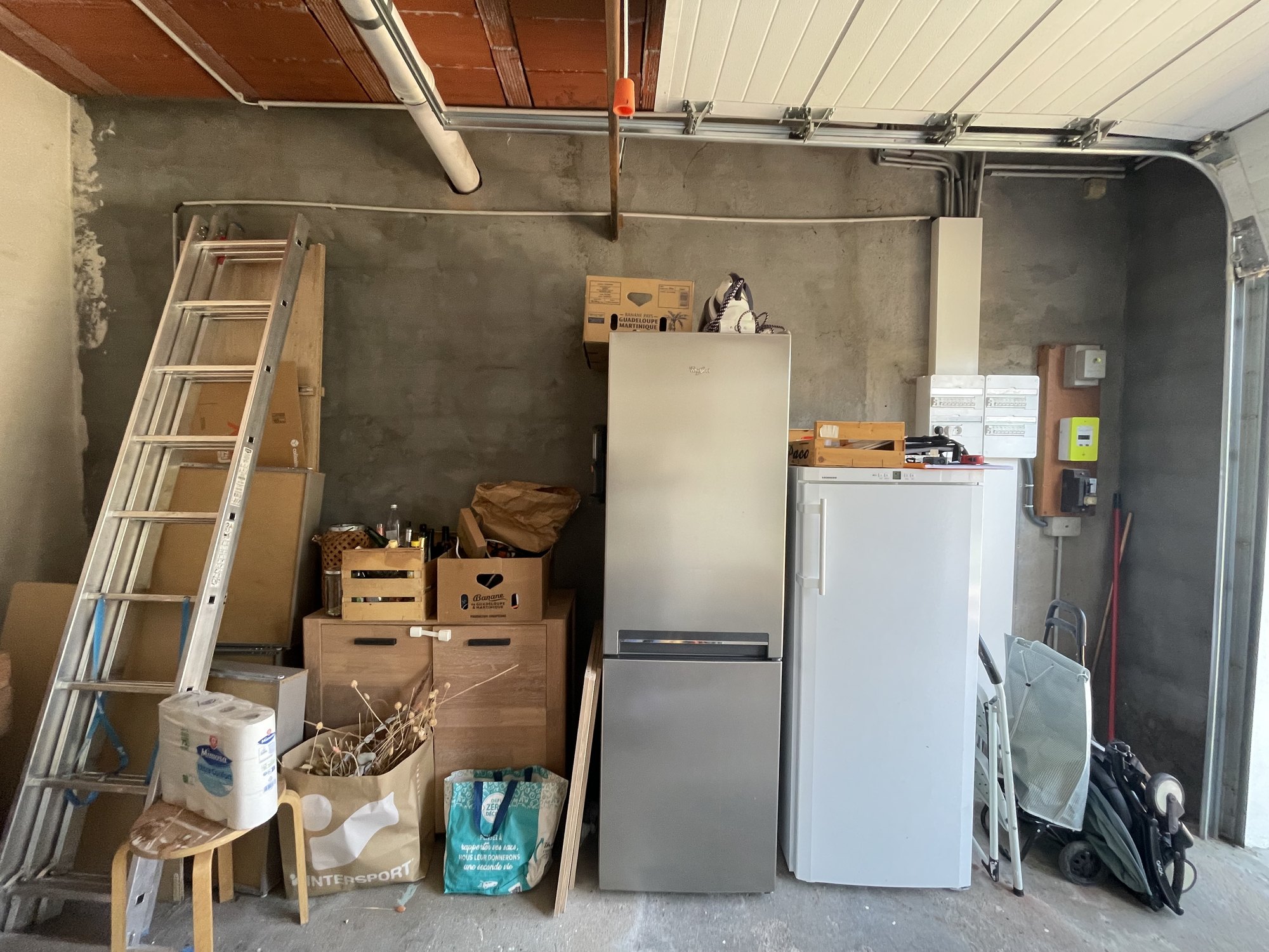 Réfrigérateur, congélateur et réserves dans le garage avant son aménagement en cellier à Yerres